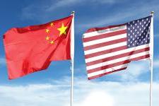 The American 和 Chinese flags fly on flagpoles side by side against a blue sky.