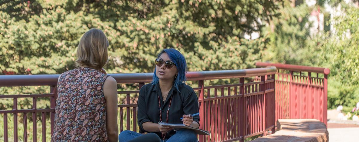 two students sitting on the side of a path